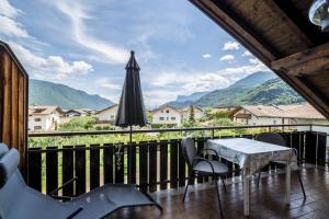 a balcony with a table and chairs and an umbrella at Apartment Gantkofel Leilichhof in Lana +8 photos