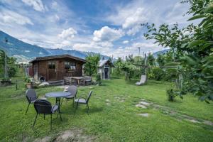 een tafel en stoelen in een tuin met een huis bij Apartment Tschigat Leilichhof in Lana di Sotto