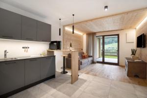 a kitchen with black cabinets and a living room at Archehof Hochzirm Lodge Franz in Campo Tures
