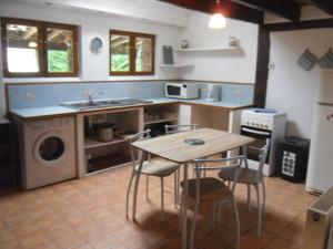 eine Küche mit einem Tisch, Stühlen und einem Waschbecken in der Unterkunft la mini ferme de maëlou in Sermaises