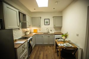 a kitchen with white cabinets and a table with plates on it at Arthur Street cottage in Hillsborough