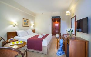 a hotel room with a bed and a tv at Odysseia Hotel Kapetanios in Limassol
