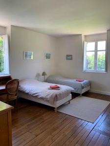 a bedroom with two beds and two windows at Aile Château La Chapelle du Bois des Faulx in La Chapelle-du-Bois-des-Faulx