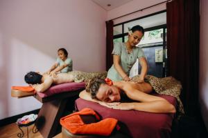 a woman laying on a bed while two women are standing at Full Moon Villa Ubud in Ubud