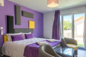 ein lila Schlafzimmer mit einem Bett und einem Stuhl in der Unterkunft Hôtel Domaine des Pierres Dorées in Ternand