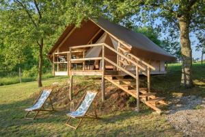 a tree house with two chairs and a roof at Natura Camp Karli in Kaštelir