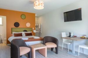 ein Schlafzimmer mit einem Bett, 2 Stühlen und einem TV in der Unterkunft Hôtel Domaine des Pierres Dorées in Ternand