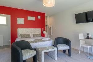 una camera con un letto con una parete rossa di Hôtel Domaine des Pierres Dorées a Ternand
