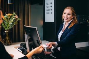 a woman in a suit shaking hands with a person in front of a computer at Stord Hotel in Stord