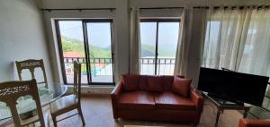 a living room with a couch and a table and a television at Cozy Cottage at Afgan Lodge in Murree