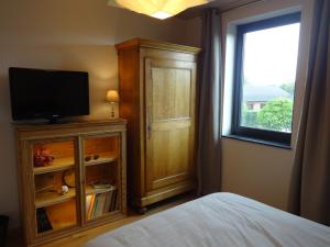 een slaapkamer met een bed, een televisie en een raam bij Chambre d'hôte Saint-Symphorien Mons in Bergen