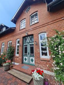 a brick house with a green door and some flowers at Der Schwalbenhof in Tetenbüll
