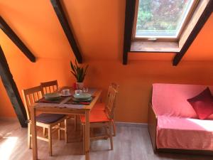 una mesa y sillas en una habitación con una pared de color naranja en Agroturystyka Pod Dębami w Klukach en Smołdzino