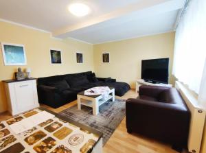 ein Wohnzimmer mit einem schwarzen Sofa und einem Flachbild-TV in der Unterkunft Ferienhaus Gonsbach in Mainz