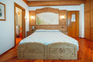 una camera con un grande letto con testiera in legno di Hotel Bel Soggiorno a Malosco