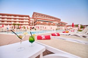 two glasses on a table next to a swimming pool at Hotel Albatros Plava Laguna in Poreč