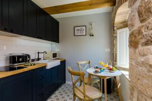 a kitchen with blue cabinets and a small table with chairs at Villa Monte Santo in Dubrovnik