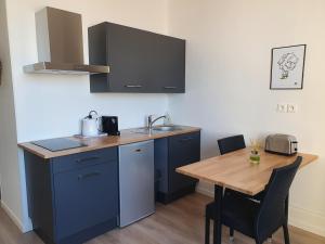 a kitchen with a wooden table with a sink and a counter at Suites Clémenceau in Le Havre