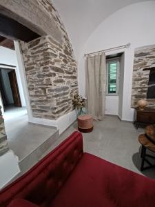 a living room with a red couch and a stone wall at Casa Pernice in Penta-di-Casinca