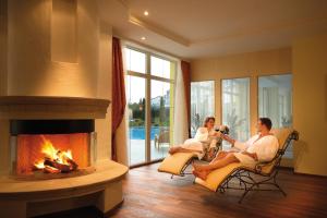 two women sitting in chairs in a living room with a fireplace at Parkhotel in Bad Schallerbach