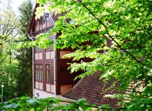 a tall building with a lot of trees in front of it at Ezüstfenyő Hotel in Telkibánya