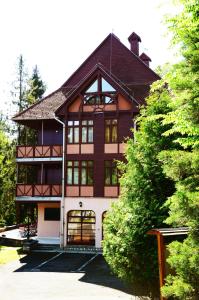 a large brown and white house with trees at Ezüstfenyő Hotel in Telkibánya