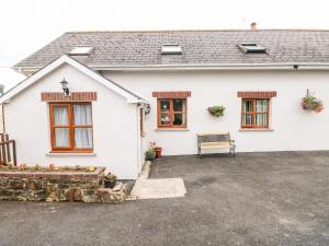 Uma casa branca com um banco à frente. em Stable Cottage em Haverfordwest