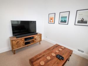 sala de estar con TV y mesa de centro de madera. en Stanegarth, en Keswick