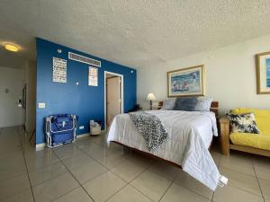 um quarto com uma cama e uma parede azul em Tropical Studio at the Beach in Isla Verde em San Juan