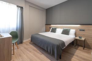 a bedroom with a bed and a table and a window at Alda Centro Pamplona in Pamplona