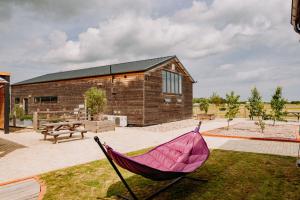 a pink hammock sitting in the grass in front of a building at Creeksea Place Barns in Burnham on Crouch