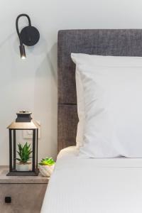 a bed with a white pillow and a lamp on a table at Raise Heraklion Boutique Apartments in Heraklio