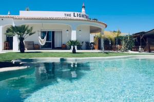 a villa with a swimming pool in front of a house at The Lighthouse Hostel in Sagres
