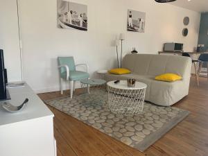een woonkamer met een bank en een tafel en stoelen bij L'Annexe, F2, 800 m de la plage in Donville-les-Bains