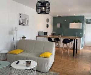 ein Wohnzimmer mit einem Sofa und einem Tisch in der Unterkunft L'Annexe, F2, 800 m de la plage in Donville-les-Bains