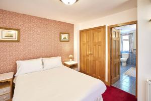 a bedroom with a white bed and a bathroom at Host & Stay - The Cottage Barn in Skipton