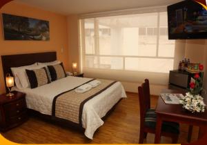 a bedroom with a bed and a desk and a window at Hotel Xilon Resort Pasto in Pasto