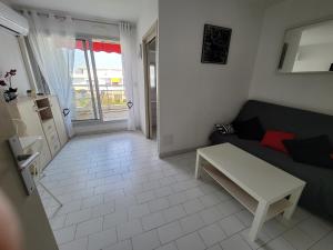 a living room with a couch and a table at Studio cabine climatisé avec parking au Couchant in La Grande Motte