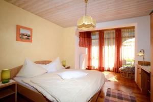 a bedroom with a bed with white sheets and a large window at Appartementhaus Angerer - Feriendomizile Pichler in Heiligenblut