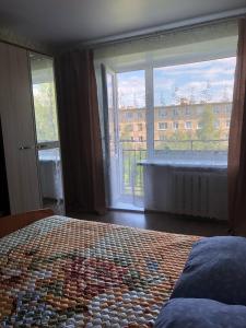 a bedroom with a bed and a large window at Уютная 2 -х комнатная квартира в центре Кеми in Kem