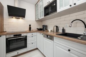 una cocina con armarios blancos y fregadero en Apartamenty Północna by Renters en Darłowo
