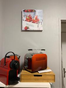 un tostapane rosso seduto sopra un tavolo di legno di RESIDENCE CEZANNE a Gréoux-les-Bains 1 altra foto