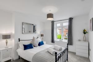 a white bedroom with a large bed with blue pillows at Modern 1bed apartment with parking in Thorpe Saint Andrew