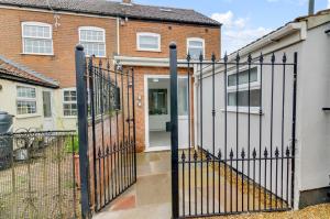 a gate in front of a house with a building at Modern 1bed apartment with parking in Thorpe Saint Andrew