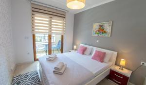 a bedroom with a large white bed with pink pillows at Apartment Light De Luxe - with Old Bridge view in Mostar