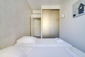 Luxurious apartment with sea view - Cannes في كان: سرير أبيض في غرفة مع خزانة