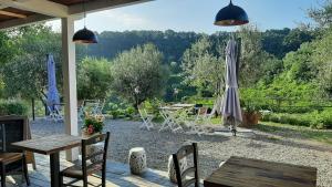 patio z parasolem, stołami i krzesłami w obiekcie Bio Agriturismo Valle dei Calanchi w mieście Castiglione in Teverina