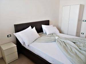 Una cama con sábanas blancas y almohadas. en La Palma del Nonno, en Mazara del Vallo