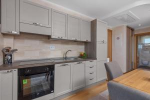 a kitchen with white cabinets and a sink and a table at Apartmani Rubinić in Turanj