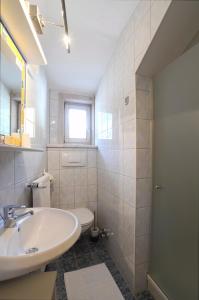 a white bathroom with a sink and a toilet at Landhaus Alpenrose - Feriendomizile Pichler in Heiligenblut